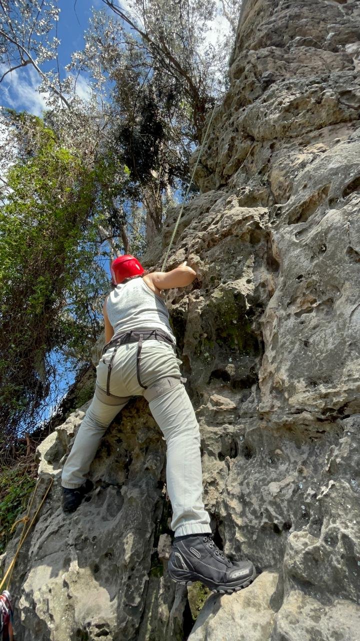 Guided rock climbing with a woman in a sandstone rock iwth helmet and rope in the nature