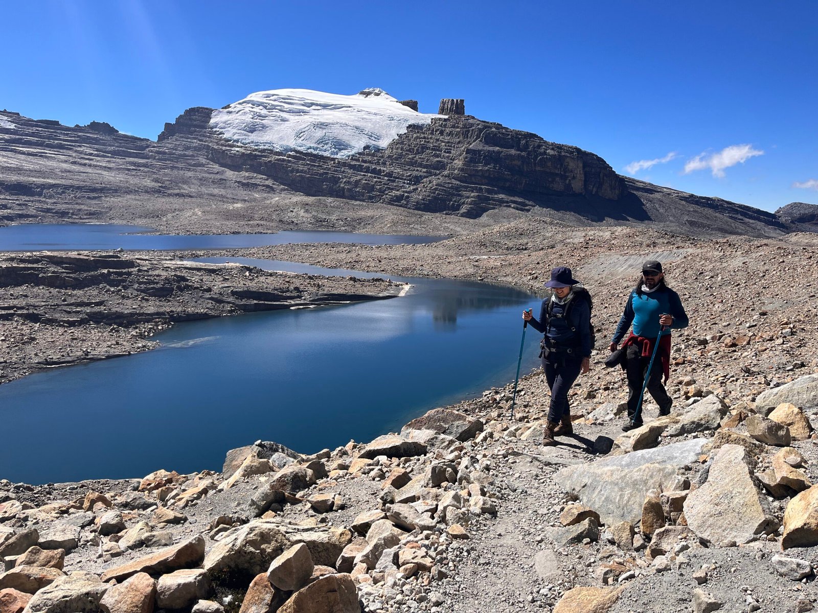Couple hiking in cocuy trail with a snow peak in the background